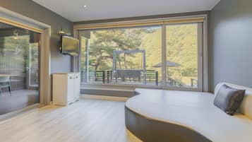 A modern room with a large sliding glass door leading to an outdoor deck, a built-in bench, and a flat-screen TV mounted on the wall.