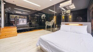 Un dormitorio moderno con una cama grande, una escultura de cebra y un muro de vidrio con vistas al exterior.