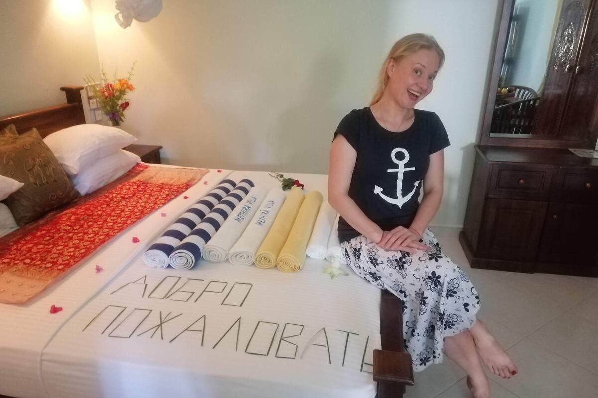 A bed with rolled towels, a decorative pillow, and a message written on the bedspread.