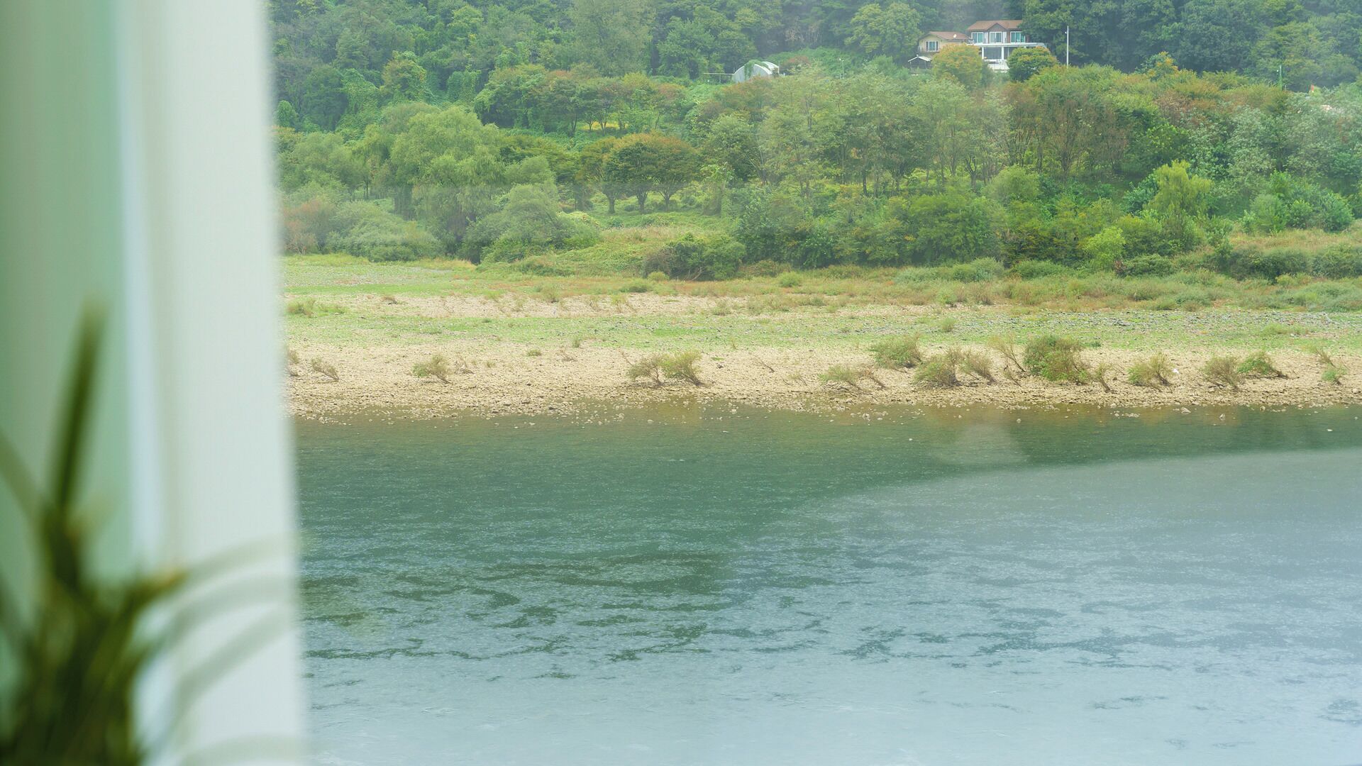 Un río con una casa en una colina al fondo.