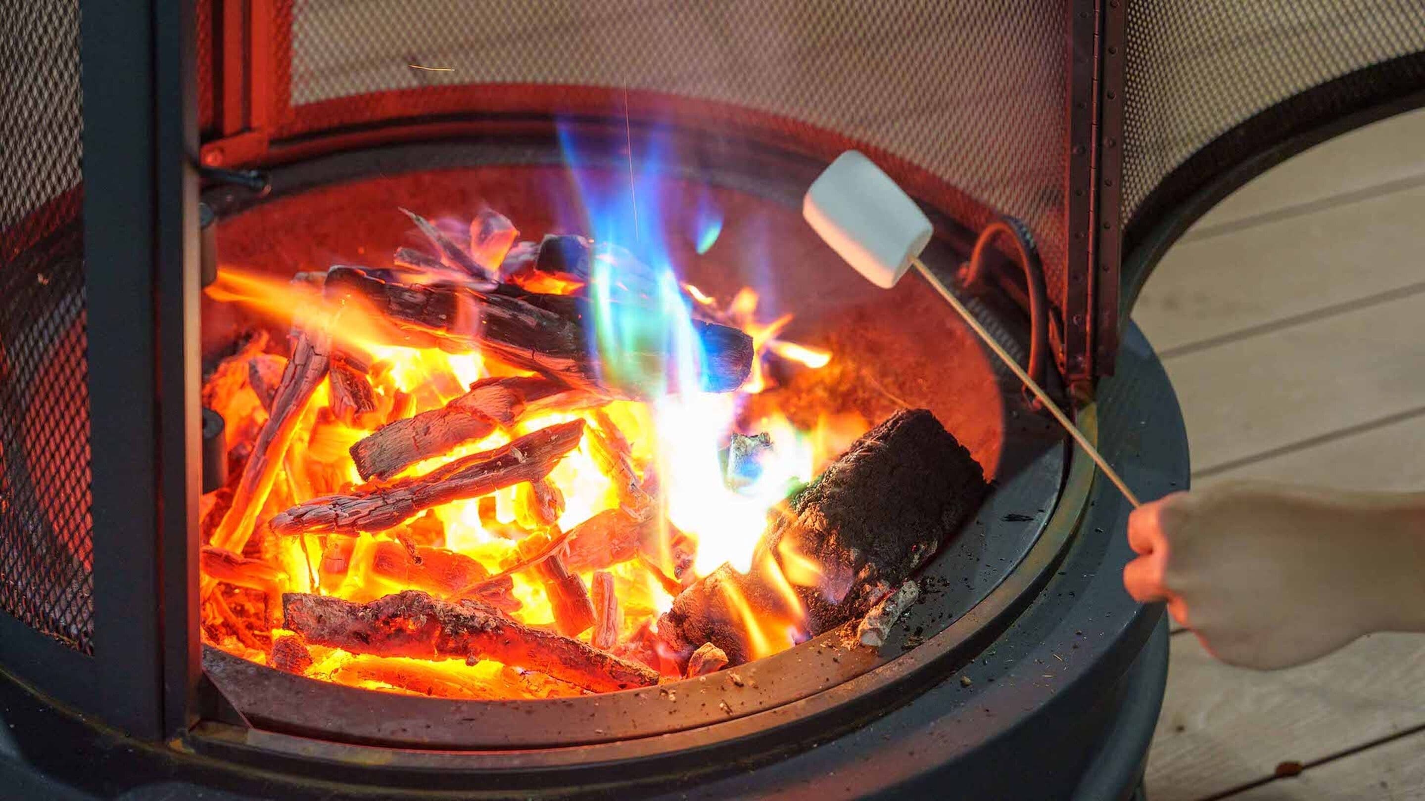 Feuerstelle mit brennendem Holz und einem Marshmallow am Spieß.