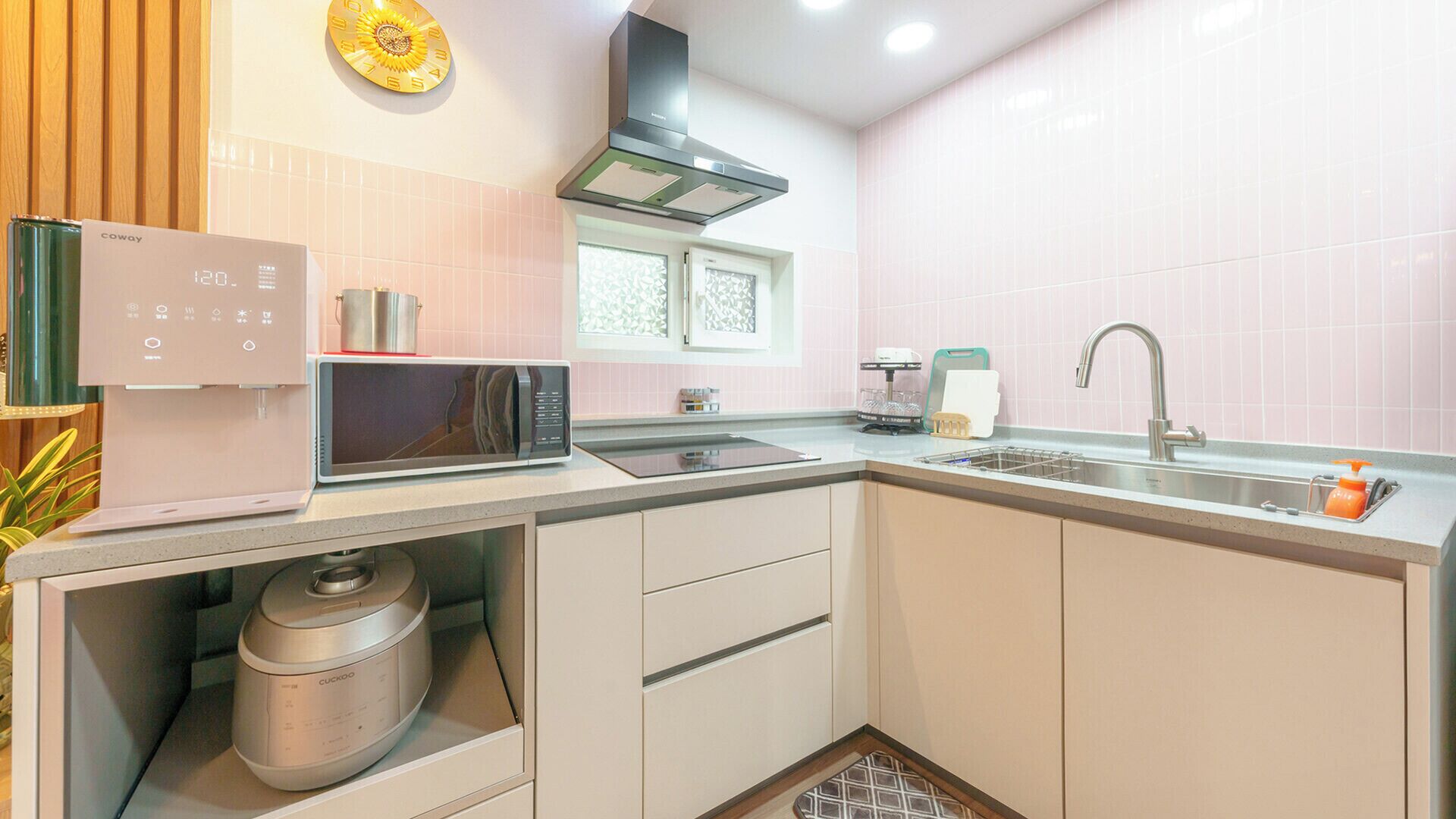 Una cocina compacta equipada con microondas, hervidor, pileta y horno integrado.