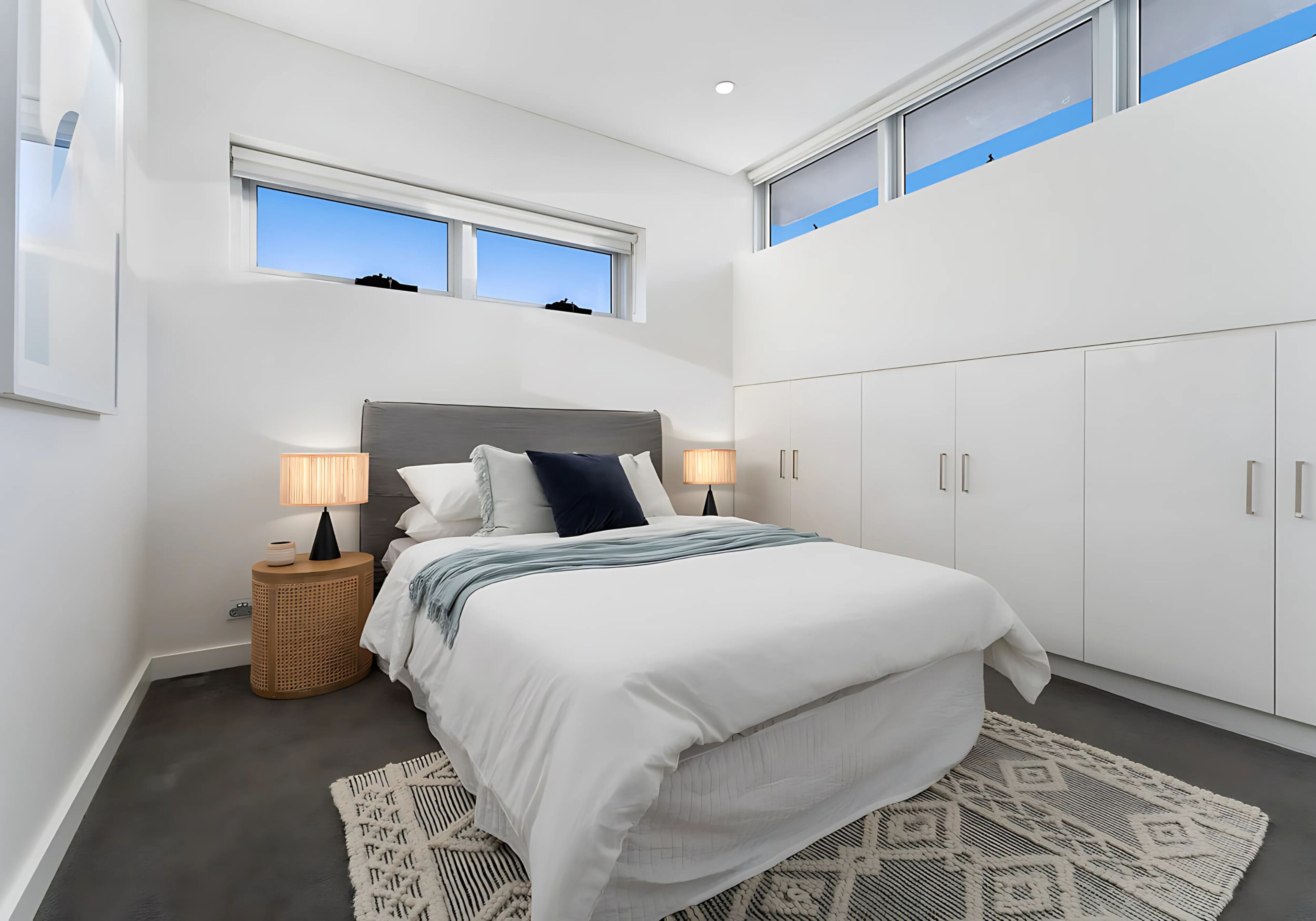 A bedroom with a bed, bedside lamps, a window, and a wardrobe.