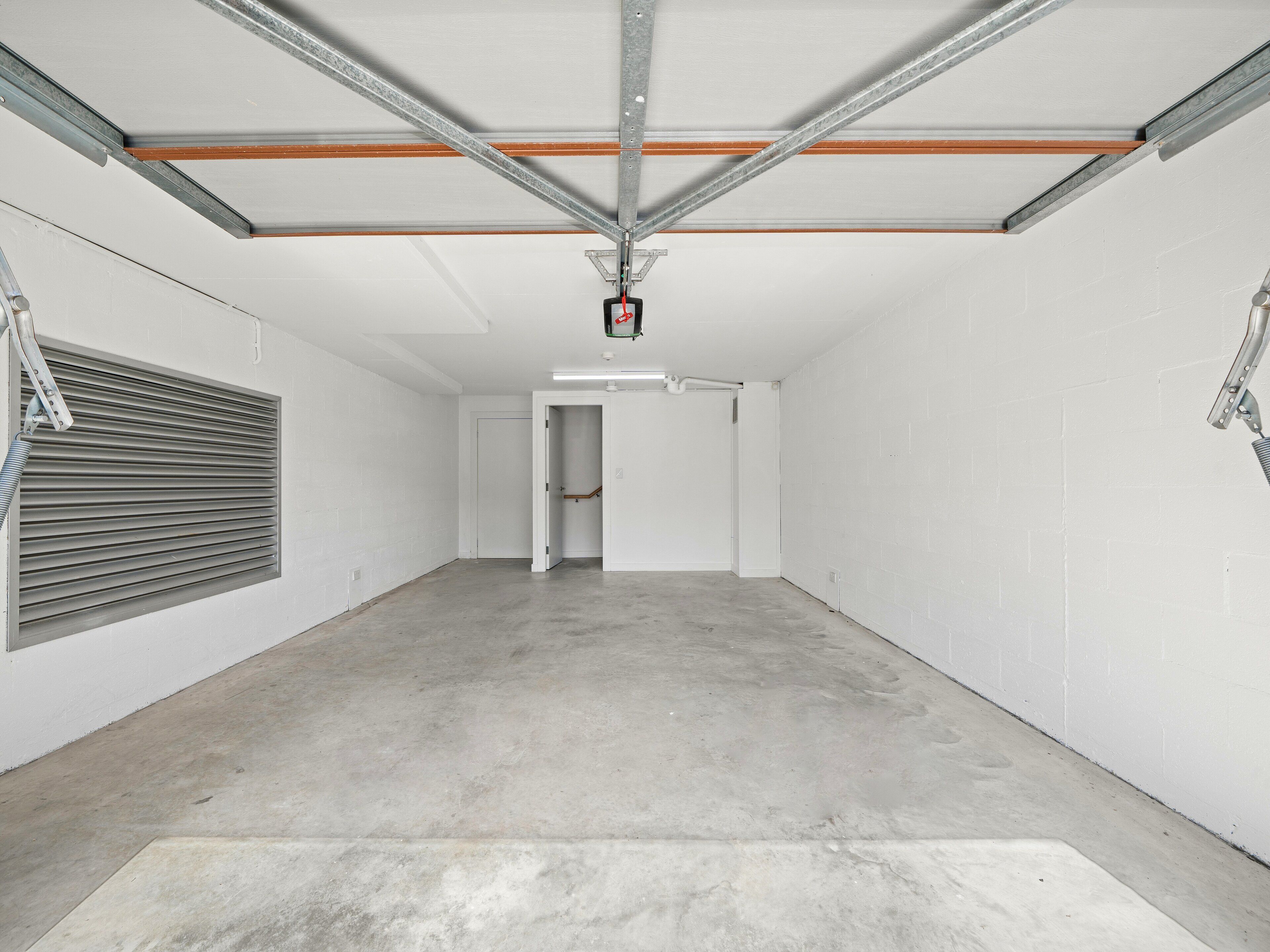 A spacious, empty garage with white walls and a concrete floor.
