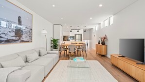 Una sala de estar moderna con sofá, mesa de centro, televisor y comedor con sillas y mesa.