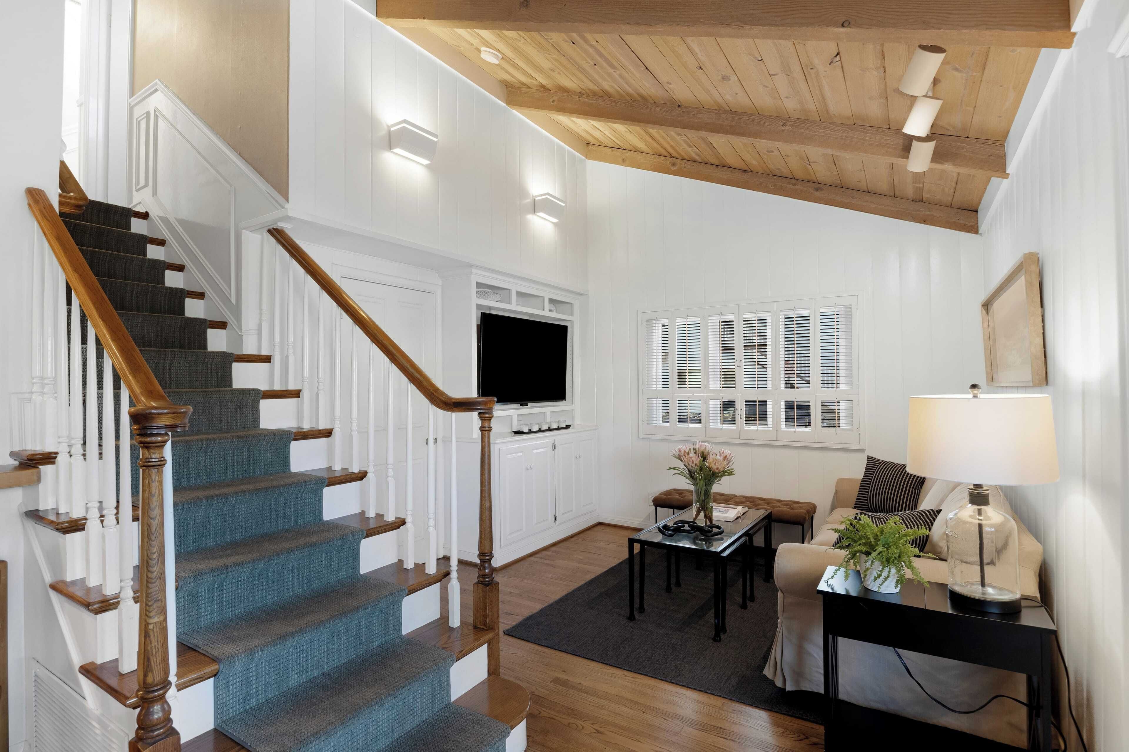 A staircase with wooden railings and blue carpet leading to a white door.