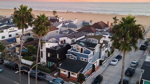Zona residencial costera con casas, palmeras y una playa al fondo.