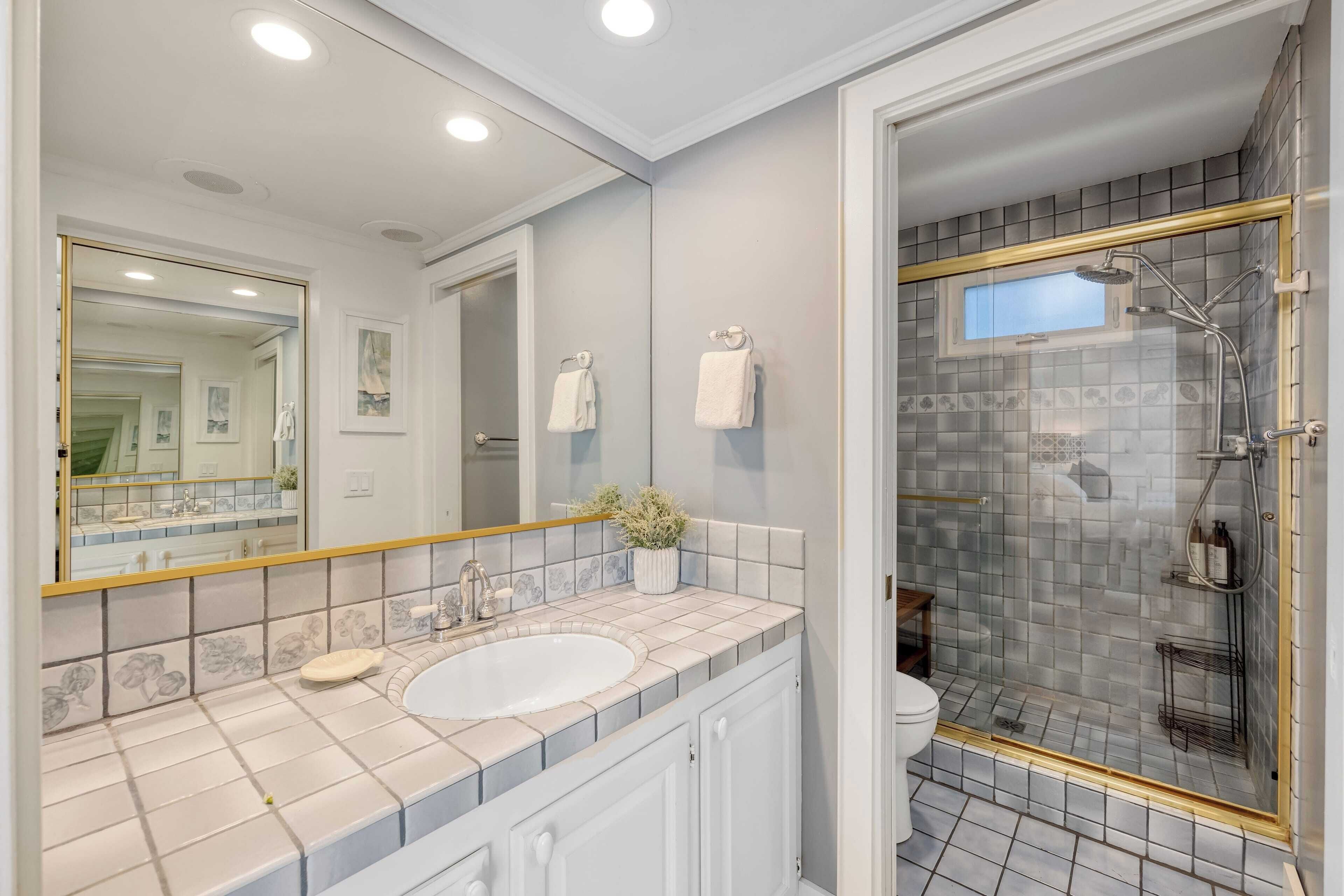 Un baño con un espejo grande, un lavamanos y una zona de ducha.