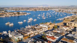 A marina with numerous boats docked, surrounded by residential buildings with a clear view of the city skyline in the background. - Twin Dolphins by Avantstay Steps to Beach Deck (Newport Beach)