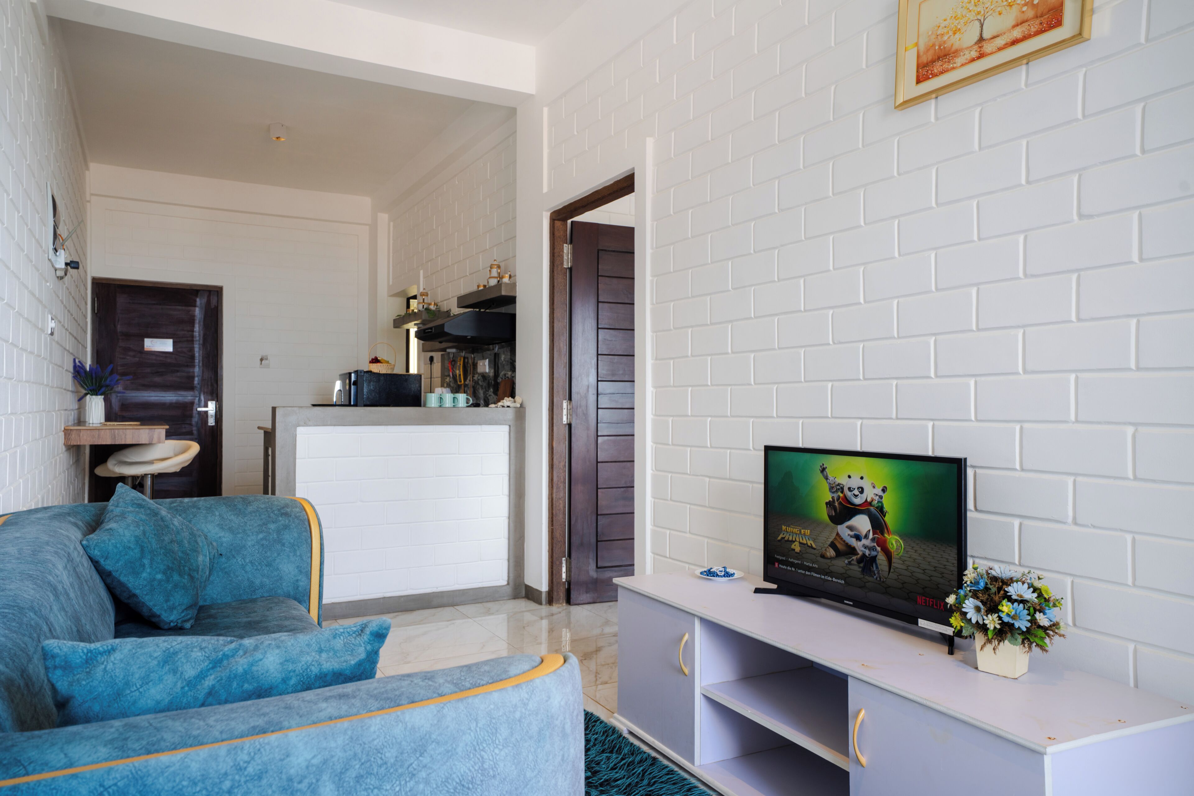 A living room with a sofa, a television, and a small table with a flower vase.