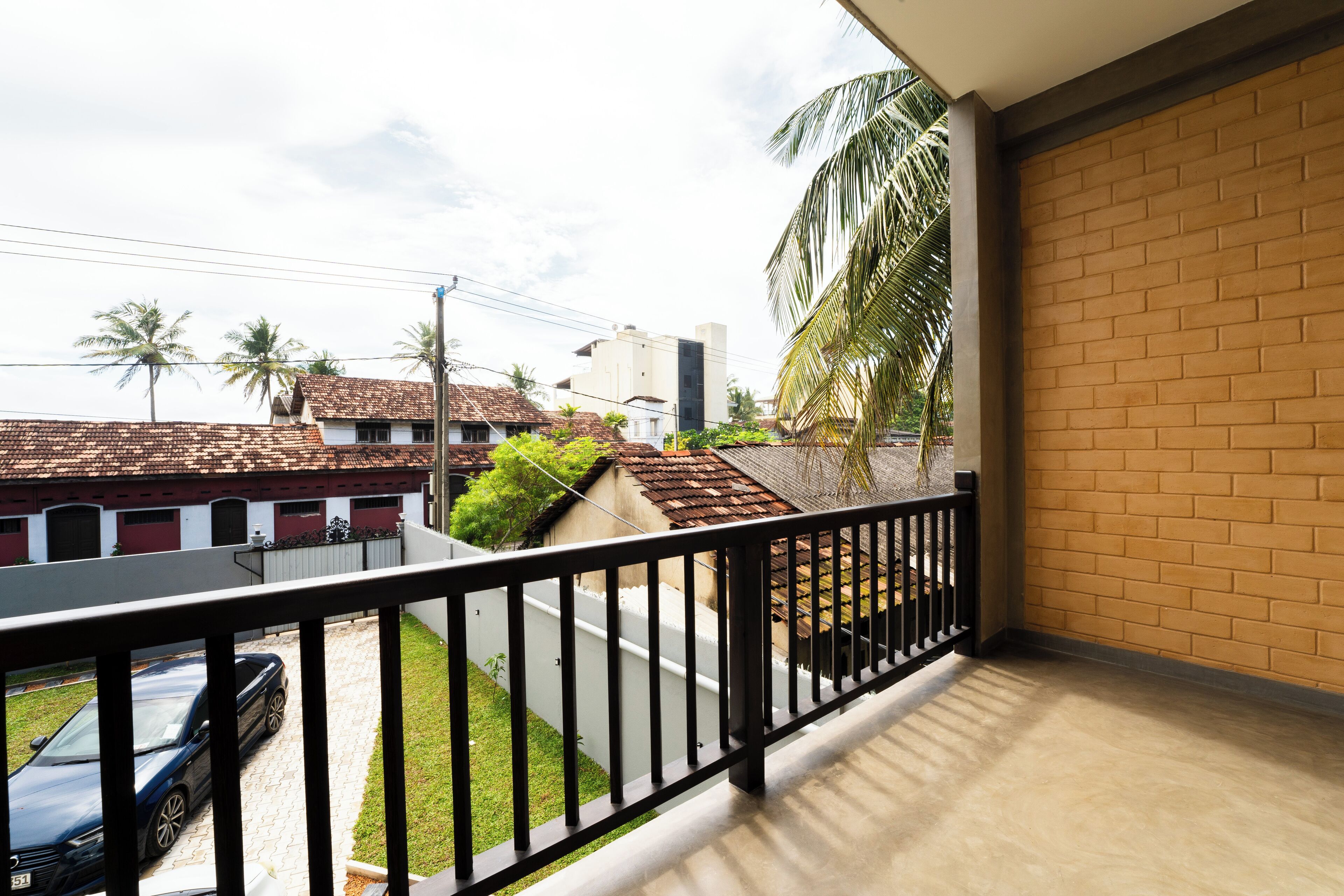 Un balcon donnant sur un quartier résidentiel, avec vue sur des maisons et une voiture.