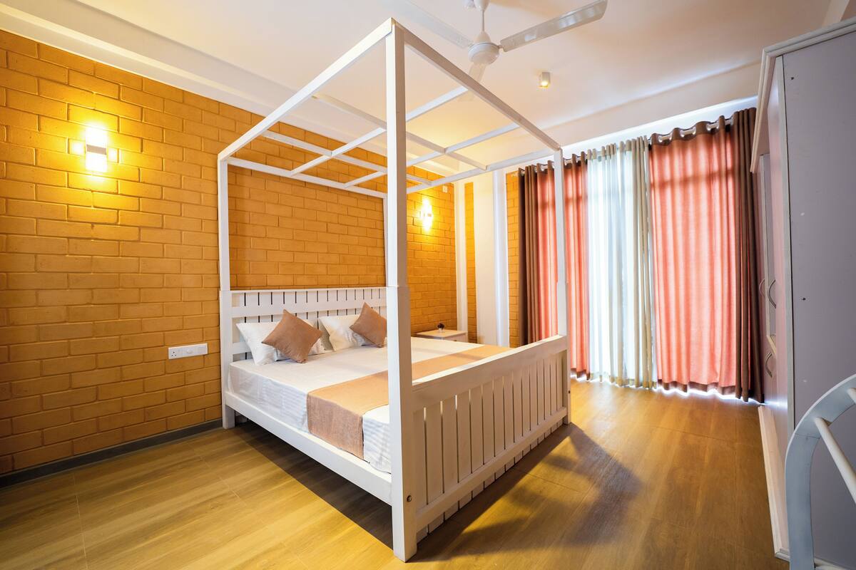 Un lit à baldaquin avec une tête de lit en bois, un mur en briques et un plancher en bois.