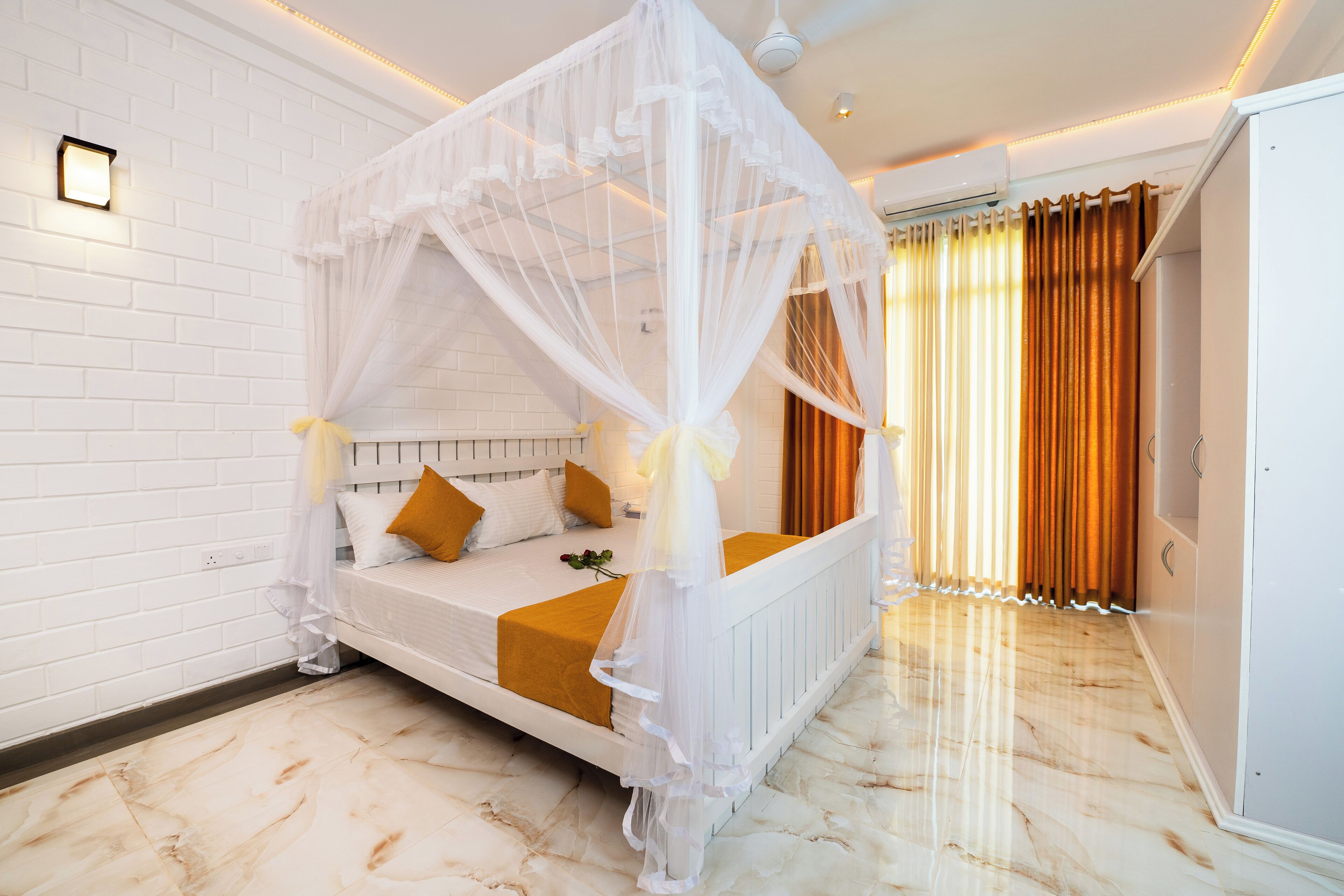 Un dormitorio con cama con dosel, paredes blancas y suelo de mármol.