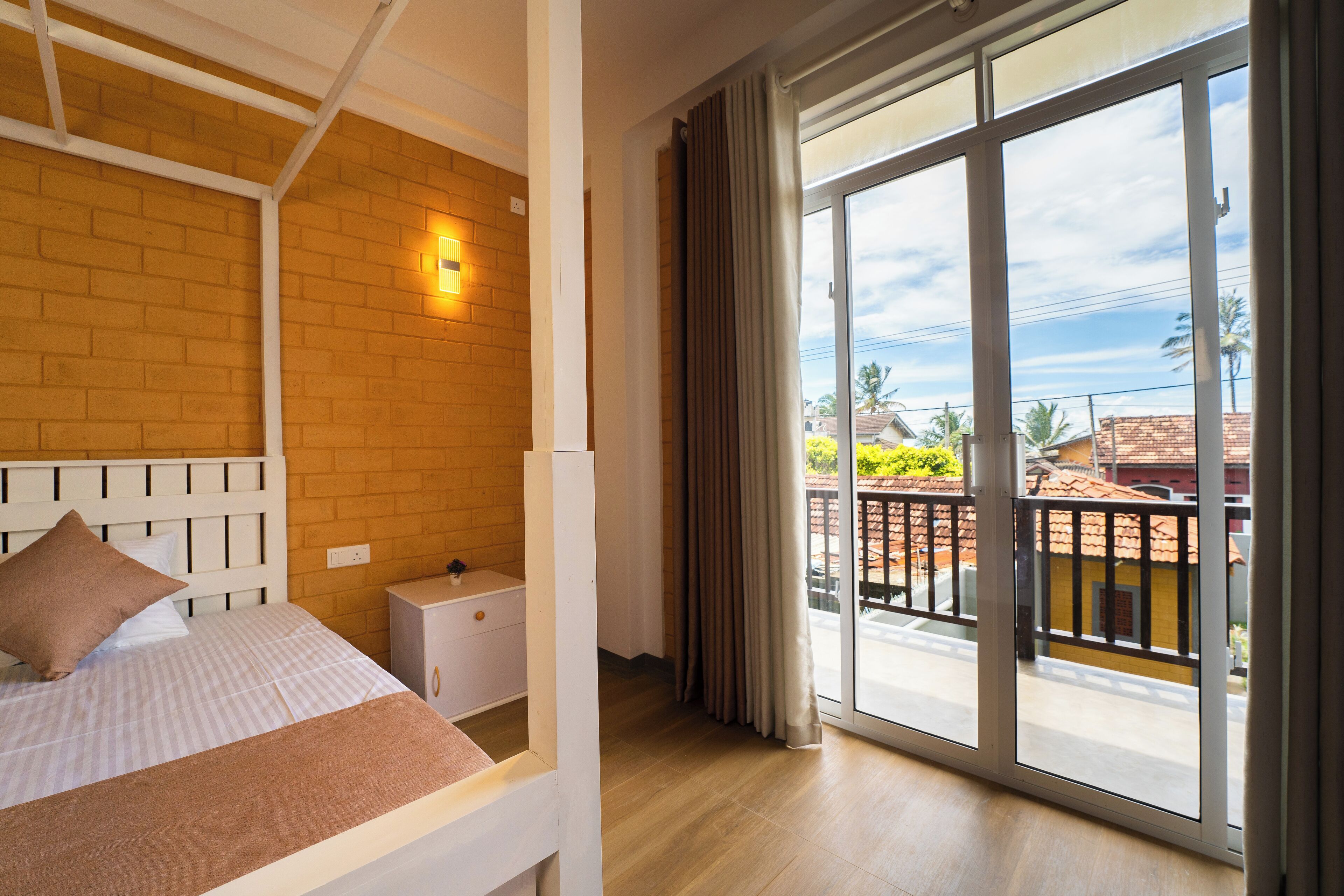 Ein Schlafzimmer mit einer großen Glasschiebetür, die auf einen Balkon führt, einem Bett mit Kopfteil und einem Nachttisch.