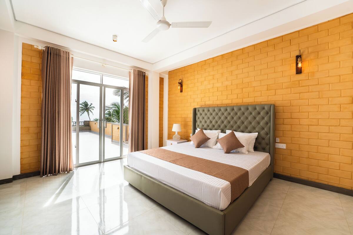 Une chambre d’hôtel moderne avec un grand lit, un ventilateur de plafond et un mur en briques.