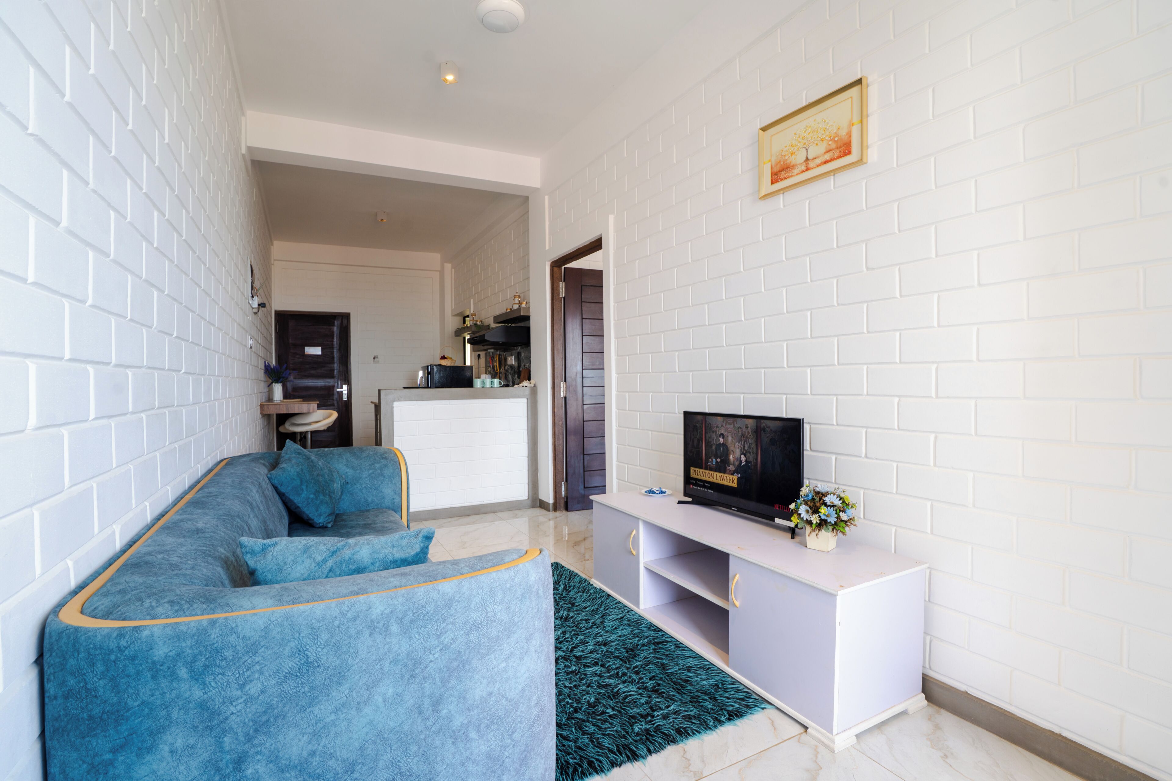A living room with a sofa, TV, and a white brick wall.