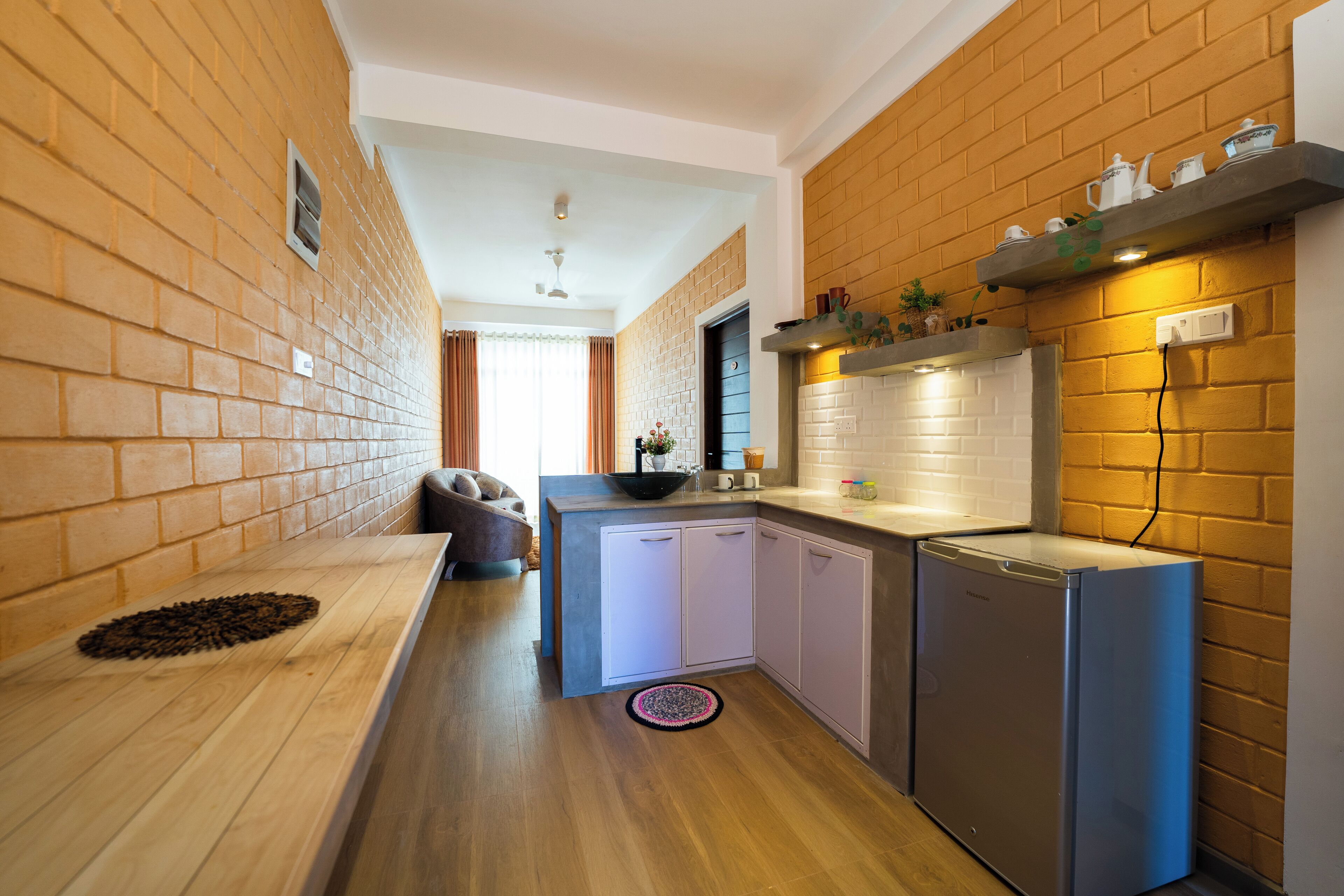 A modern kitchen with a brick wall backsplash, a built-in oven, and a small refrigerator.