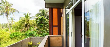 A balcony with a swimming pool, a brick wall, and a sliding glass door leading to a room.