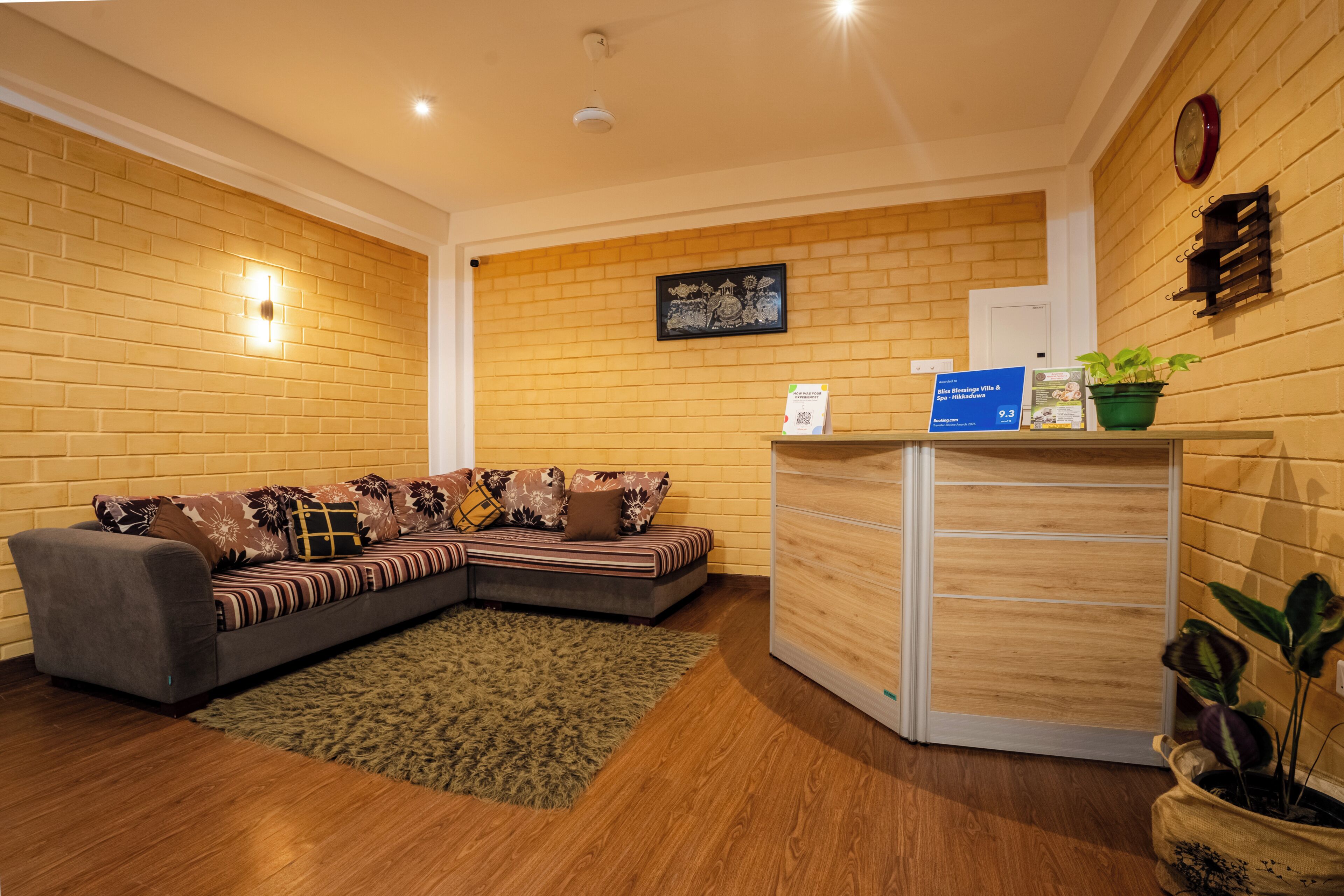 A reception area with a sofa, a wooden desk, a clock, and a framed picture on the wall.