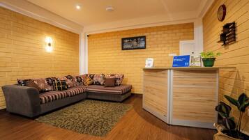 A reception area with a sofa, a wooden desk, a clock, and a framed picture on the wall.