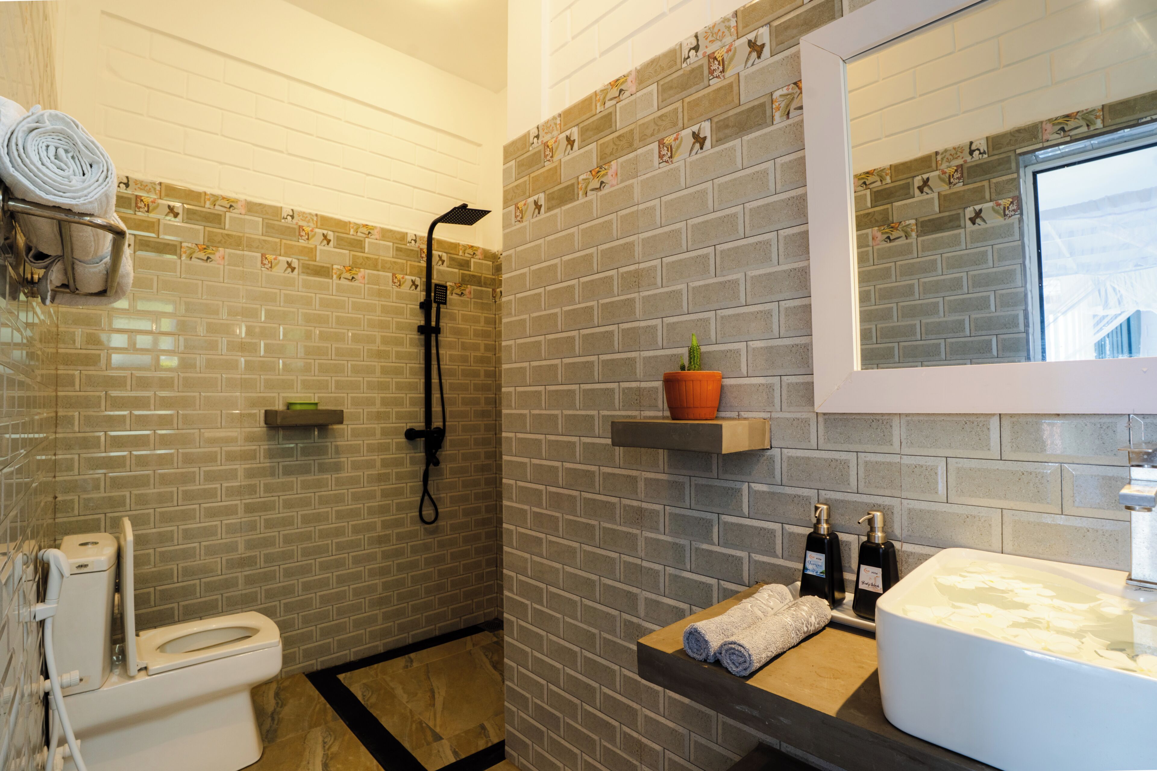 A bathroom with a toilet, shower, sink, and a mirror.