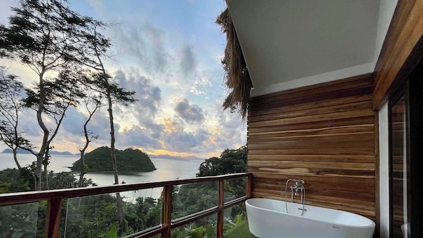 A balcony with a view of a lake and mountains, a wooden deck, and a modern bathtub. - 89 Villas Resort and Spa by Hiverooms (El Nido)