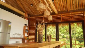 A rustic kitchen with a wooden ceiling, hanging woven light fixtures, and a large window overlooking greenery. - 89 Villas Resort and Spa by Hiverooms (El Nido)