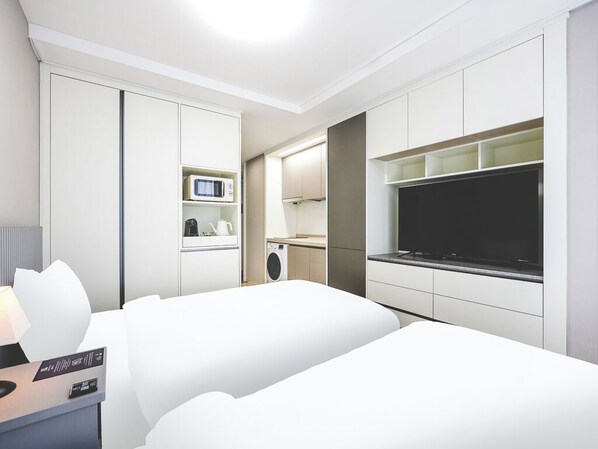 Una habitación de hotel con cama, televisor, microondas y lavadora.