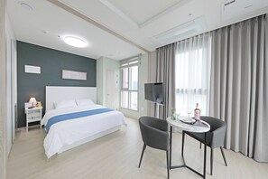 Habitació d'hotel amb llit, taula de nit, televisió i una petita taula amb una cadira.