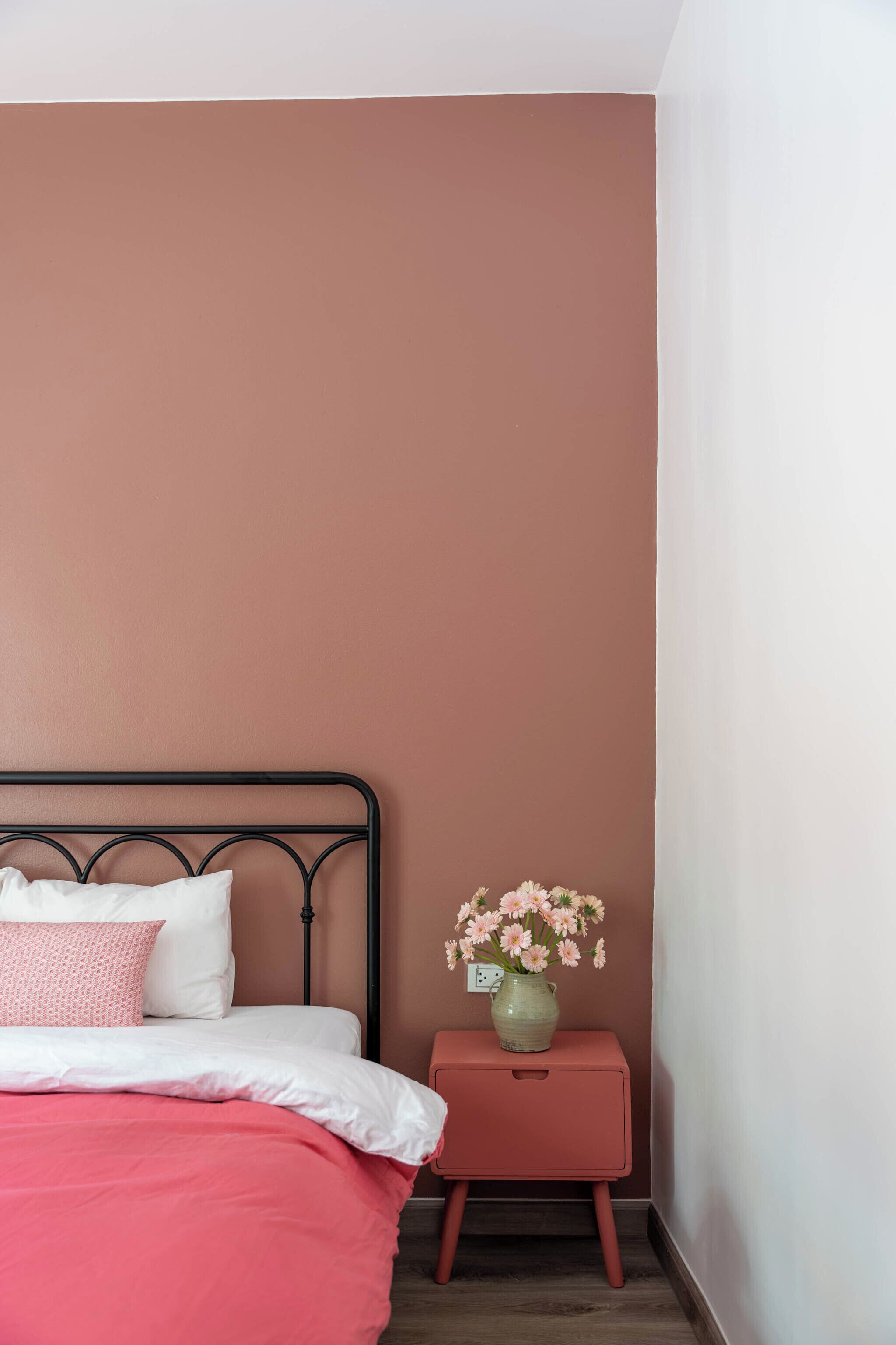 A bedroom with a bed, a nightstand, and a vase of flowers.