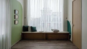 Une pièce dotée d’une grande fenêtre, d’un banc avec des coussins et d’une porte.