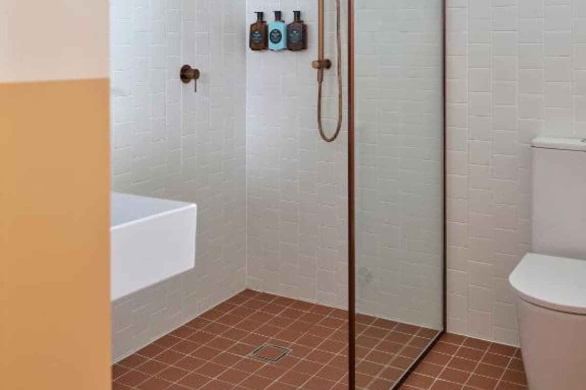 A bathroom with a glass shower enclosure, a white bathtub, and a toilet.