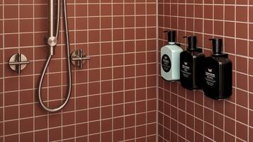 A shower with a handheld showerhead and a wall-mounted control panel.