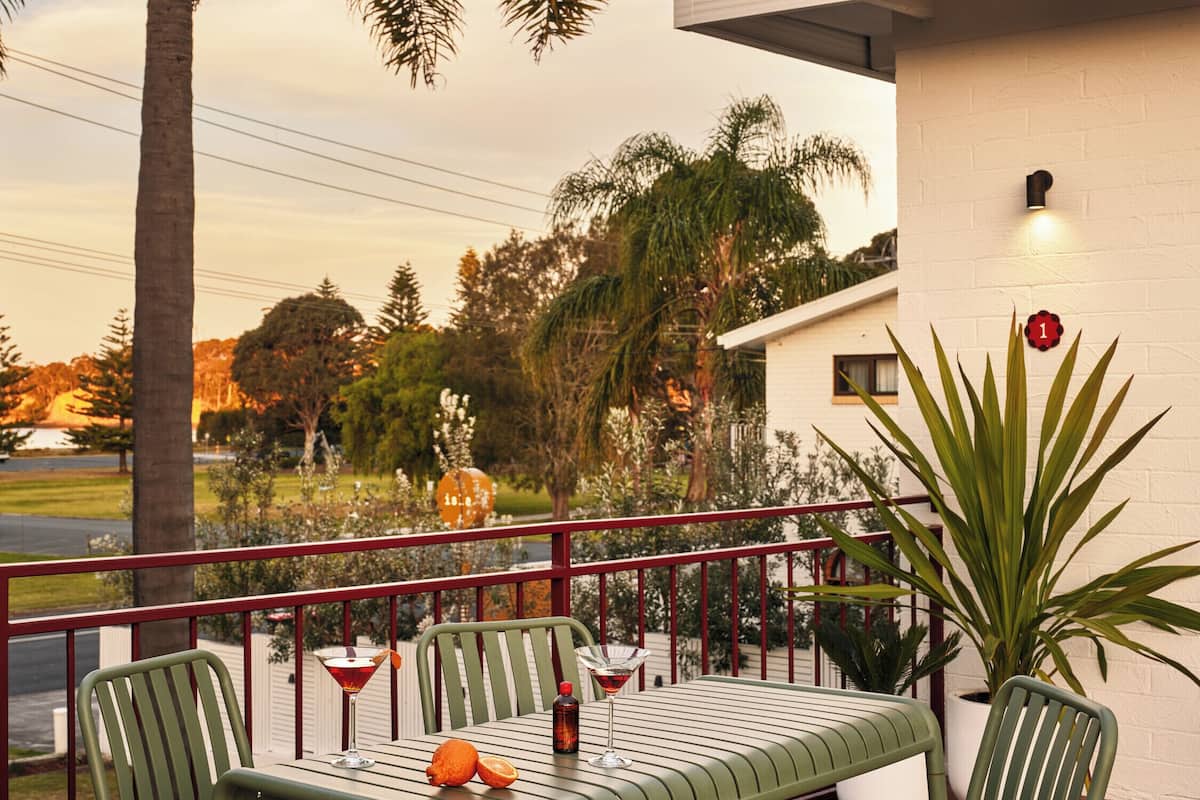 A balcony with a table and chairs, a potted plant, and a view of the surrounding area.