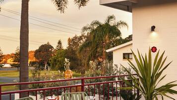A balcony with a table and chairs, a potted plant, and a view of the surrounding area.