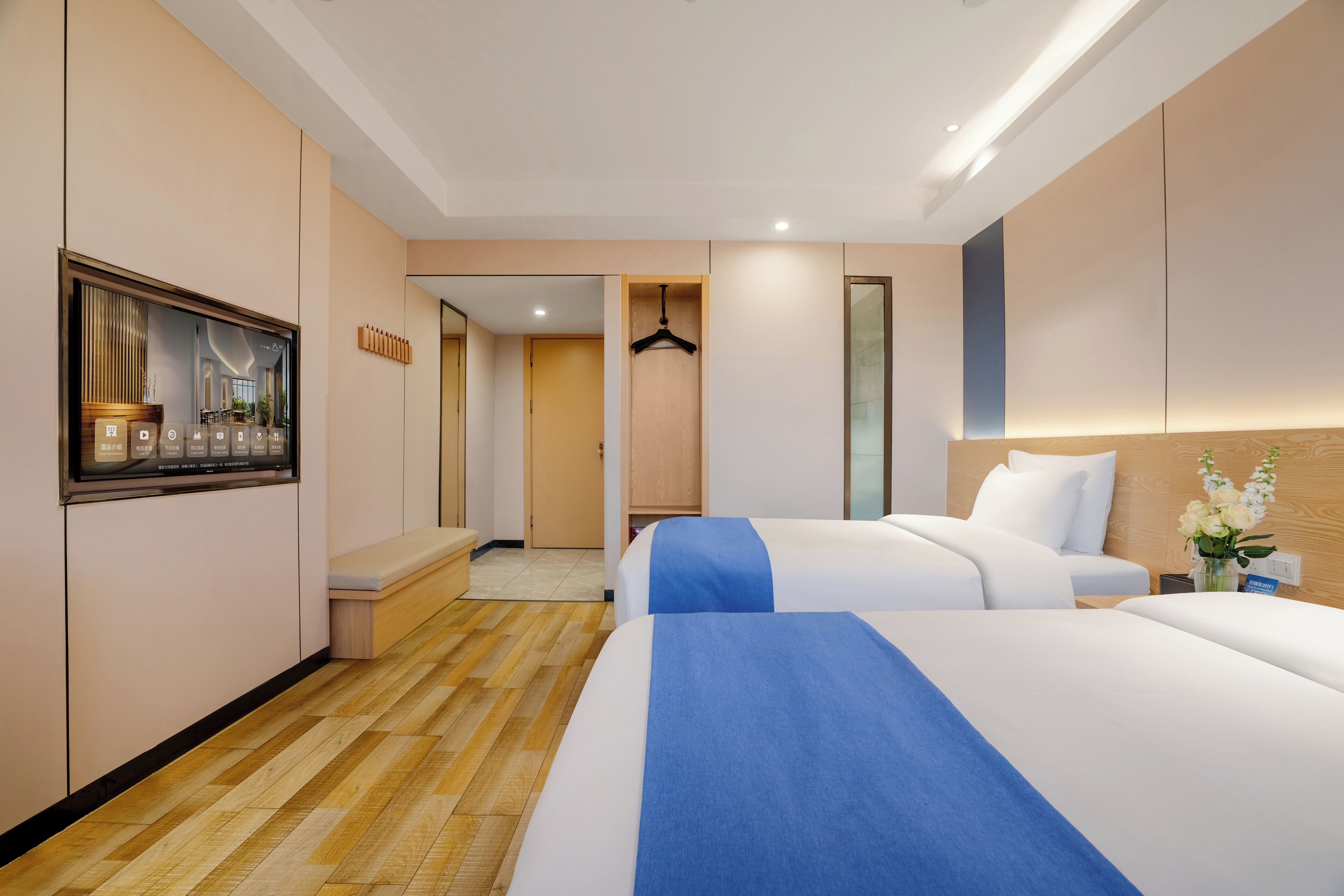 A hotel room with two beds, a seating area, a TV, and a mirror.