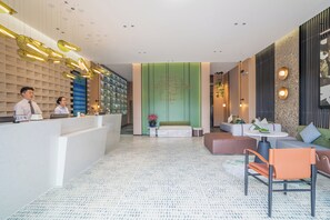 Rebedor modern d'hotel amb taulell de recepció, zona de seients i il·luminació decorativa.