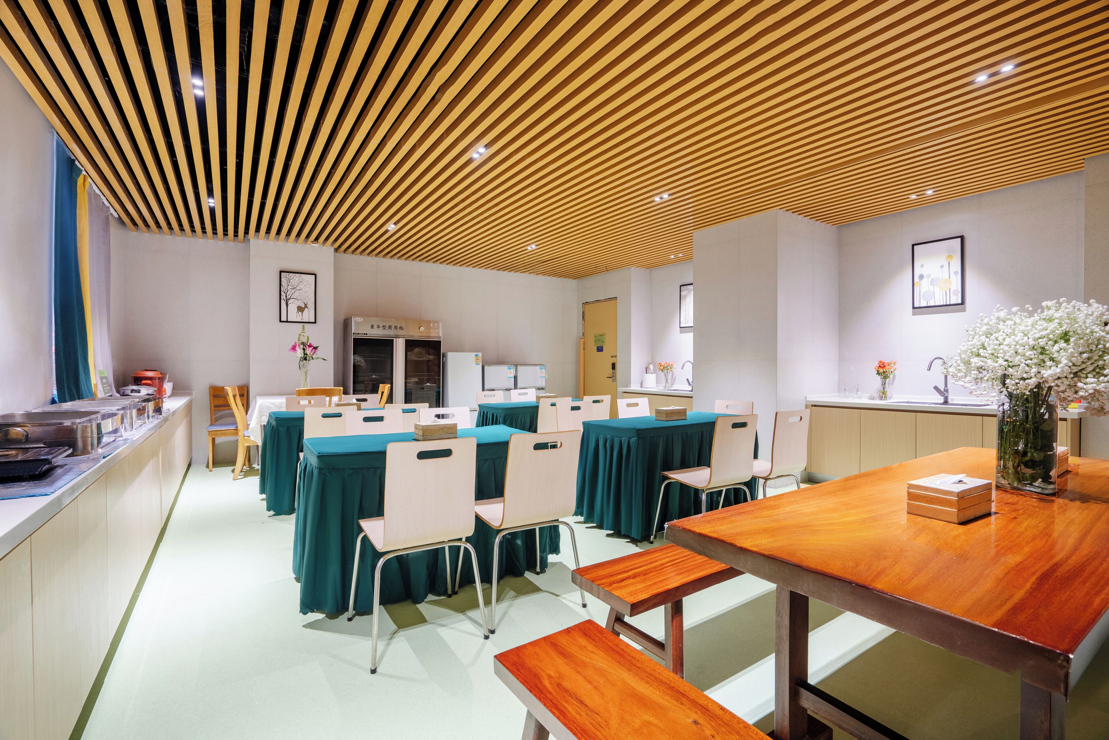 A conference room with tables, chairs, a wooden ceiling, and a counter with items on it.