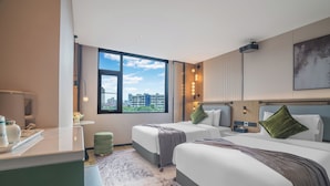 Une chambre d’hôtel avec deux lits, un bureau, une grande fenêtre et une vue sur la ville.