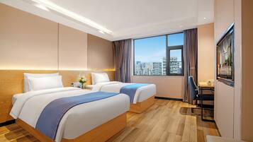 A hotel room with two beds, a desk, a chair, a TV, and a city view.