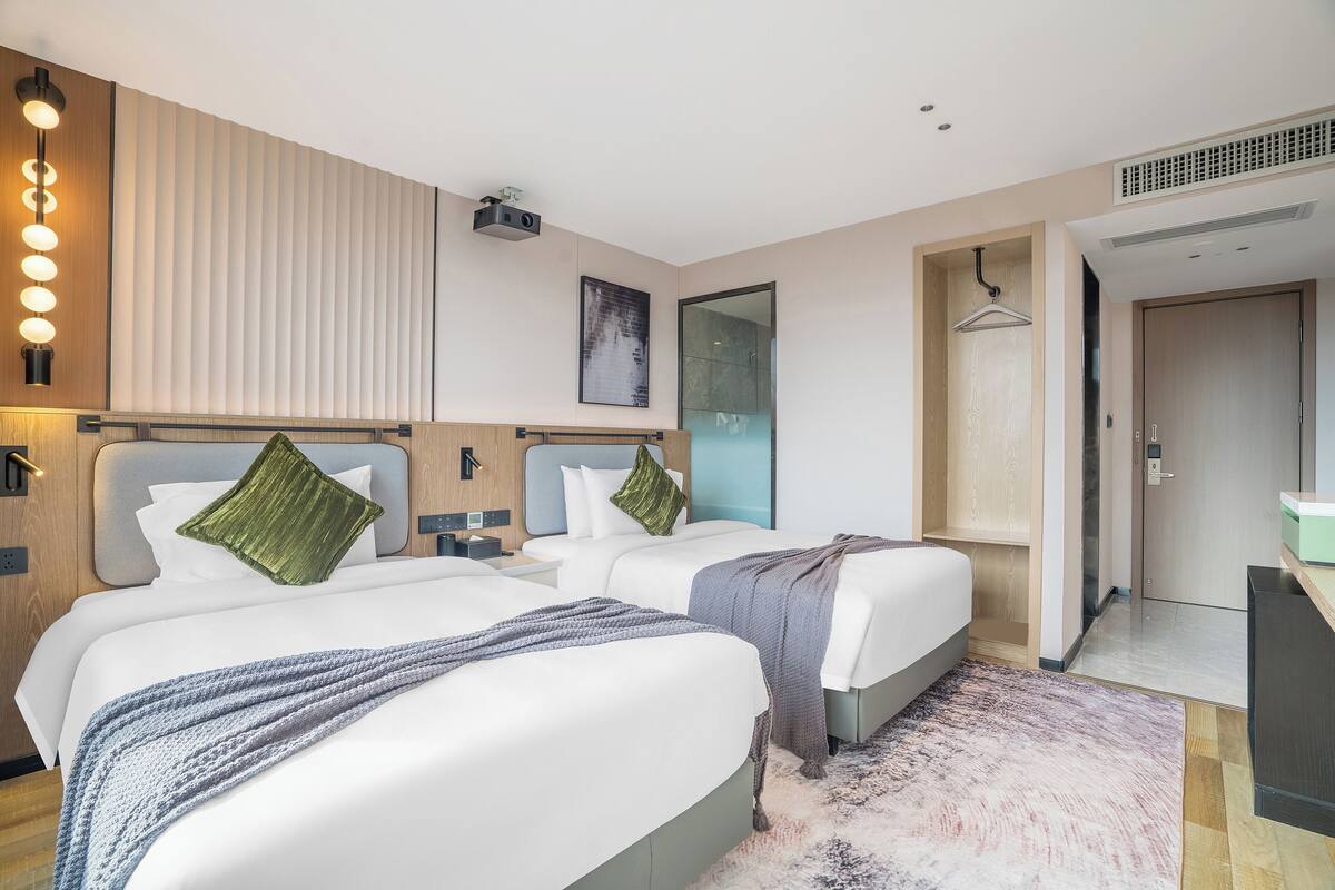 Habitación de hotel con dos camas, un espejo grande, un proyector y un vestidor.