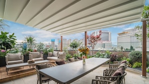 Une terrasse sur le toit, avec des sièges d’extérieur, une table et un vase rempli de fleurs.