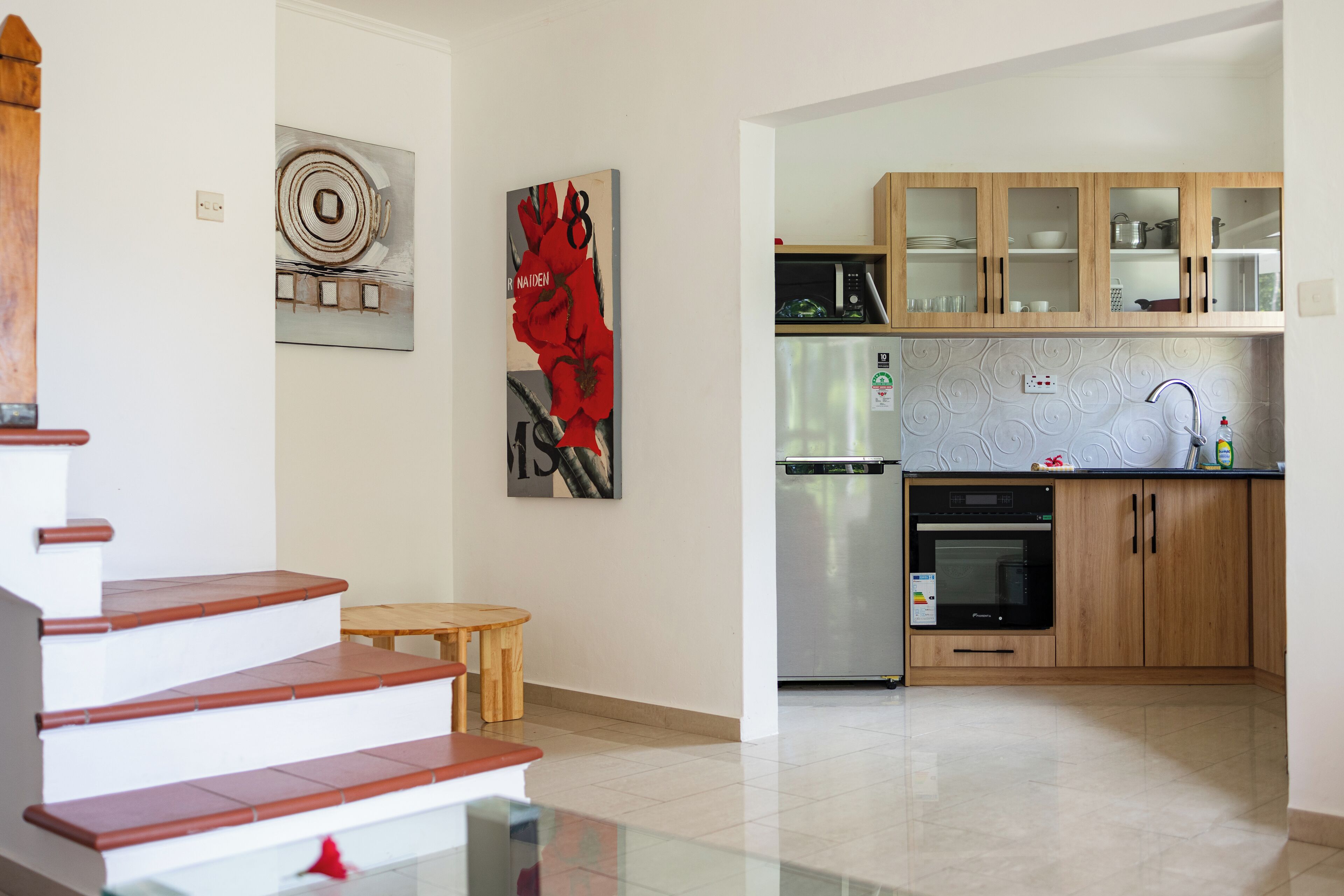 A modern kitchen with wooden cabinets, a stainless steel refrigerator, and a built-in oven.