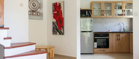 A modern kitchen with wooden cabinets, a stainless steel refrigerator, and a built-in oven.