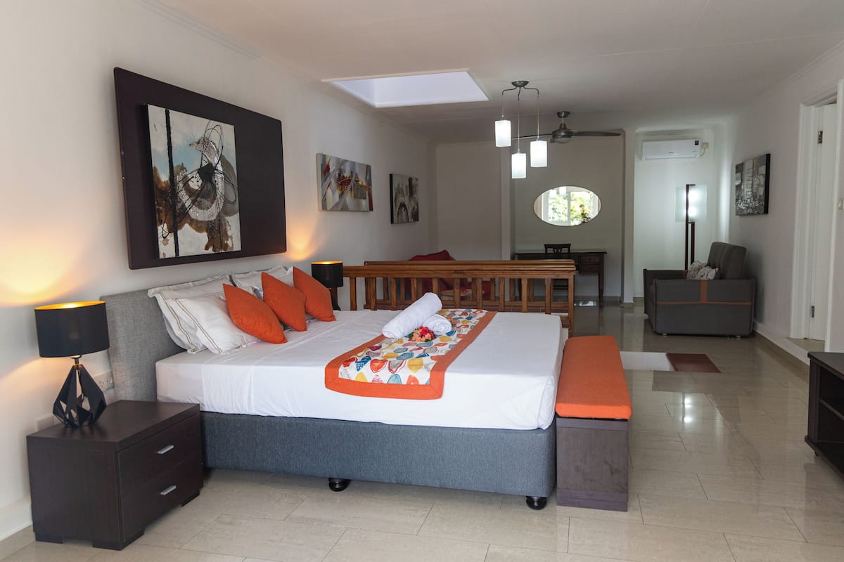 A modern bedroom with a large bed, bedside tables, a bench, and artwork on the walls.