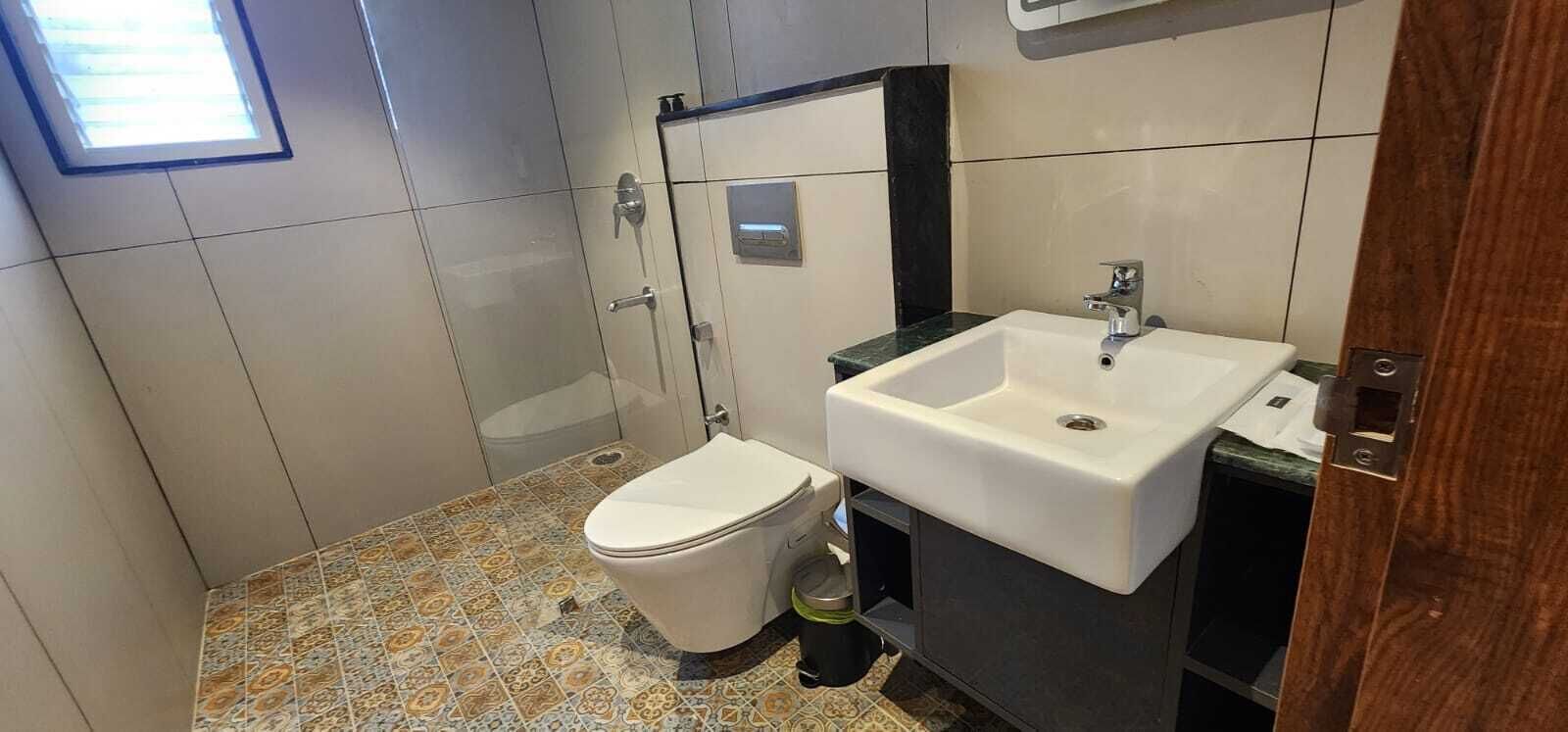 Casa de banho compacta com sanita, lavatório e chuveiro.