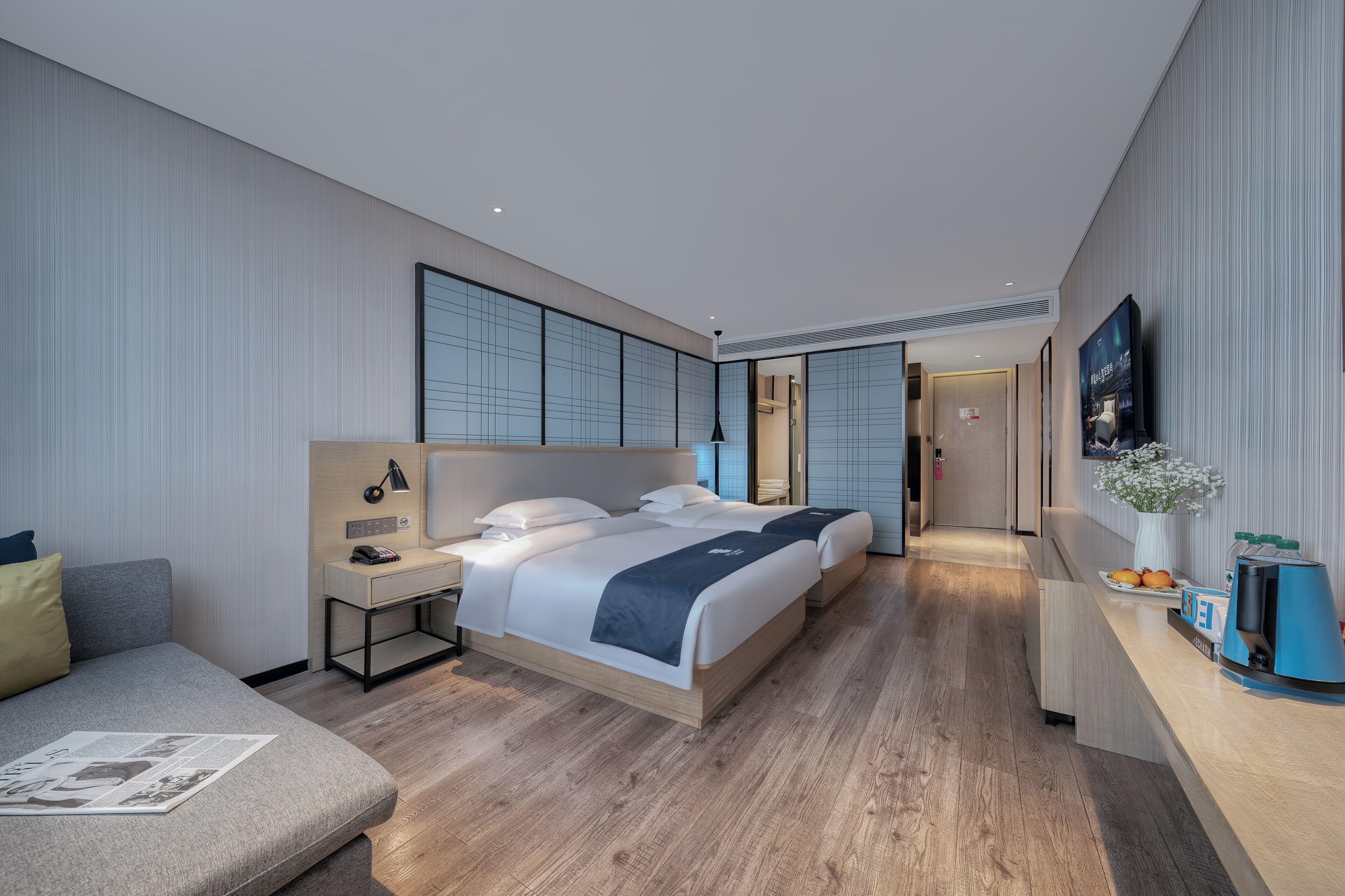 A modern hotel room with a large bed, bedside tables, a desk, and a television.