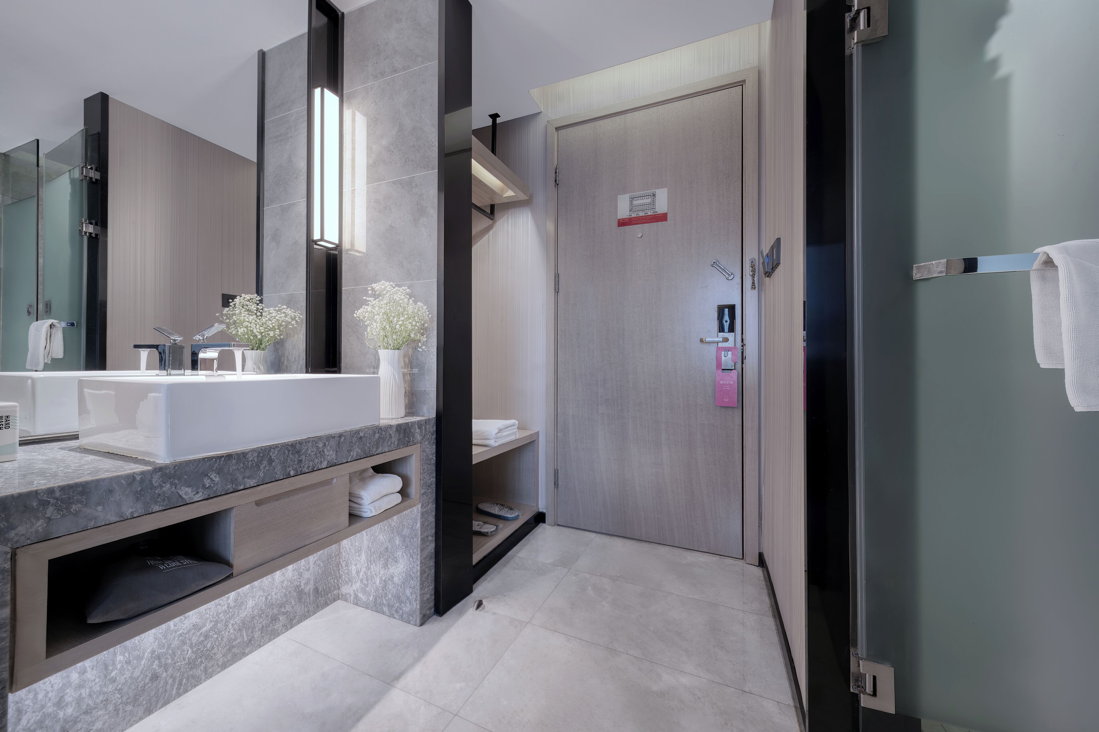 Une salle de bain moderne avec un comptoir en marbre, un grand miroir, un porte-serviettes et un espace douche.