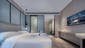 A modern hotel room with a large bed, a TV mounted on the wall, and a wooden floor. - Echarm International Hotel Pazhou Convention and Exhibition Center Nanzhou Subway Metro Branch (Guangzhou)