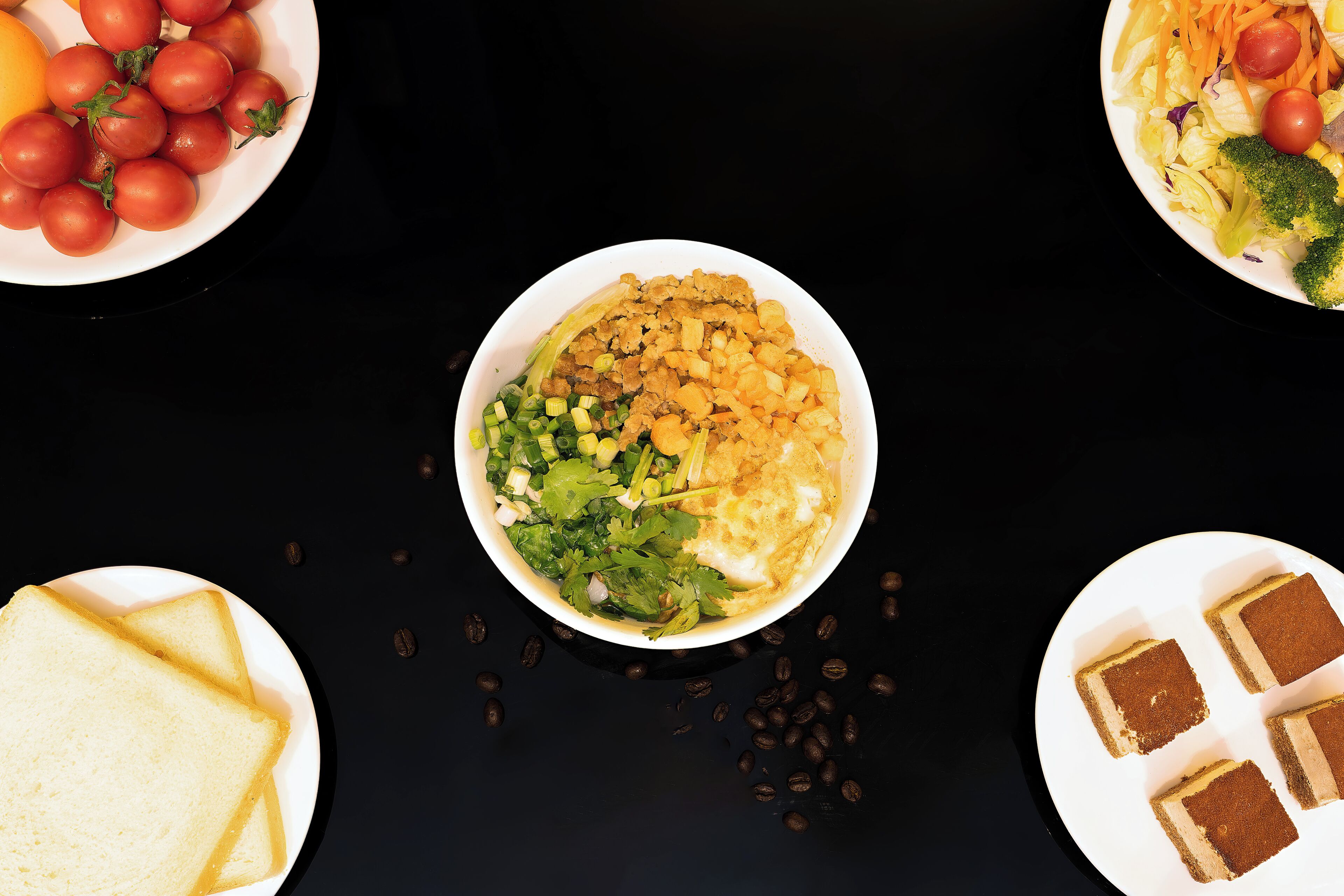 A table with various food items including a bowl of salad, plates of tomatoes, broccoli, and slices of bread.